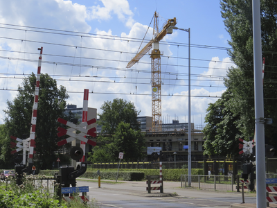 906497 Gezicht op de spoorwegovergang in de Eykmanlaan te Utrecht, met op de achtergrond de werkzaamheden voor de ...